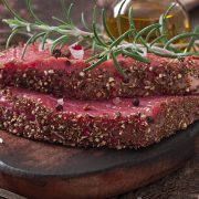 Raw beef steak with spices and a sprig of rosemary